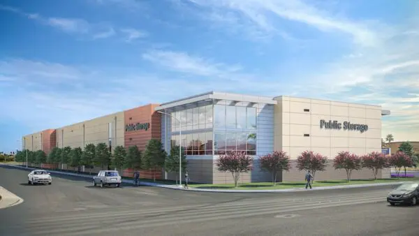 A public storage facility with modern architecture, featuring large windows and lined with trees. Cars and a few pedestrians are visible on the road in front.
