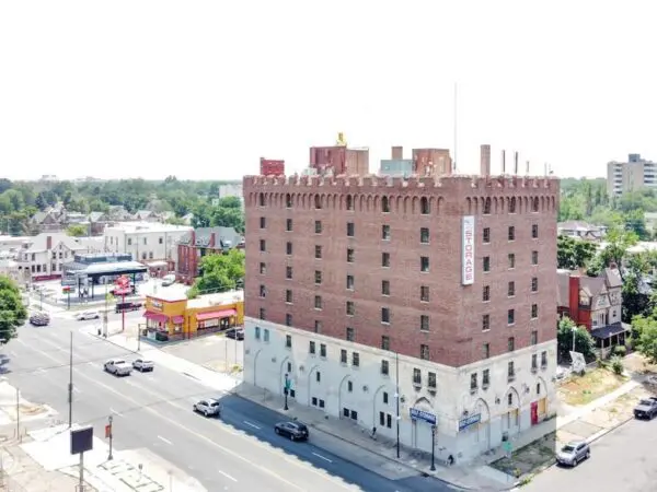 Aerial view of a large, brick building on a street corner, housing a storage facility on the lower floors. Surrounding area includes roads, trees, and smaller buildings.