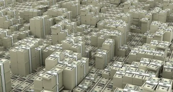 Stacks of U.S. dollar bills are arranged closely together, covering the entire floor, creating a dense field of money.
