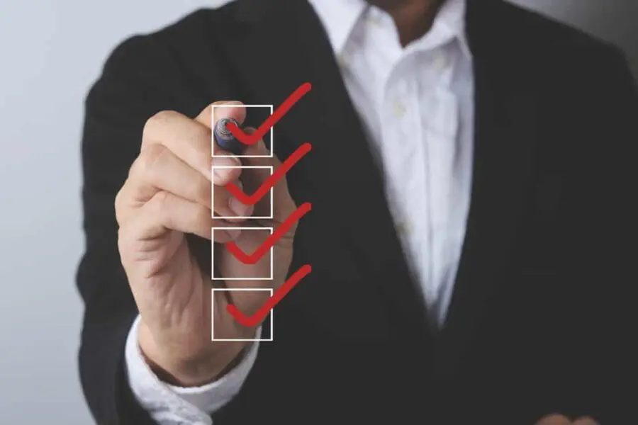 A person in a suit uses a pen to check off boxes on a glass surface.