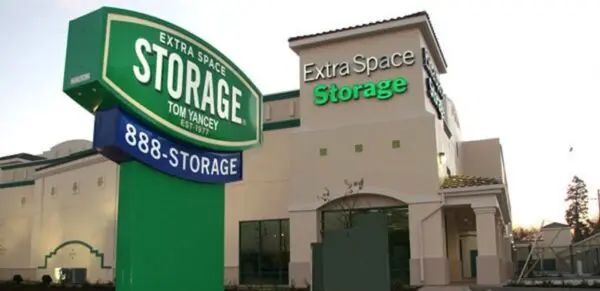 Extra Space Storage facility with a large green sign displaying contact number 888-STORAGE, set against a clear evening sky.