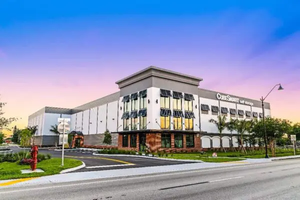 A modern, two-story CubeSmart self-storage building with a mix of glass and brick facade, situated along a suburban street under a clear dusk sky.