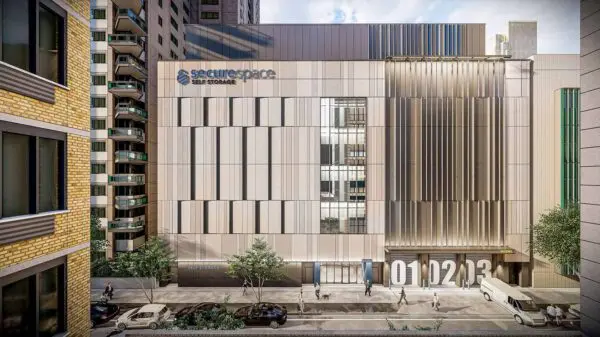 Street view of a modern building with "SecureSpace Self Storage" signage, featuring large numbers 01, 02, 03 on its facade, surrounded by tall buildings and a few pedestrians on the sidewalk.