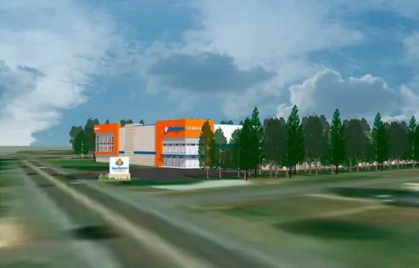 Illustration of an orange and white self-storage building surrounded by trees and a sign in a grassy area under a cloudy sky.