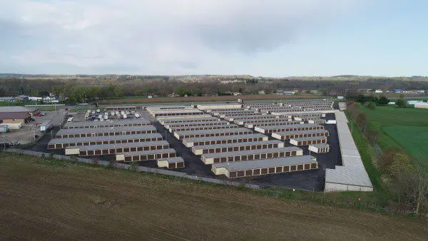 Aerial view of a large storage facility with multiple rows of identical units surrounded by rural landscape.