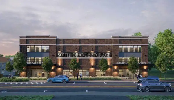 Street view of a building labeled "South Orange Storage" with cars parked in front and pedestrians on the sidewalk, surrounded by trees.