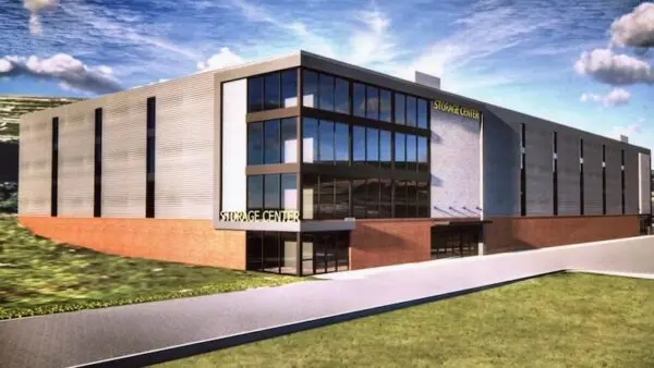 Modern storage center with large windows and brick accents, situated on a grassy area with a clear blue sky in the background.