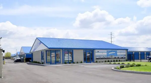 A self-storage facility with blue roofs, featuring a 24/7 rental center sign.