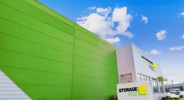 Bright green and white commercial building with "Storage Post" signage and a clear blue sky in the background.
