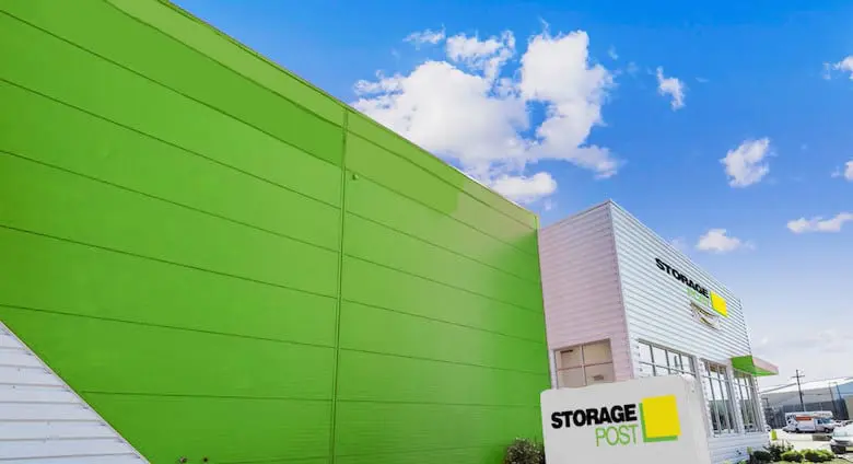 Bright green and white commercial building with "Storage Post" signage and a clear blue sky in the background.