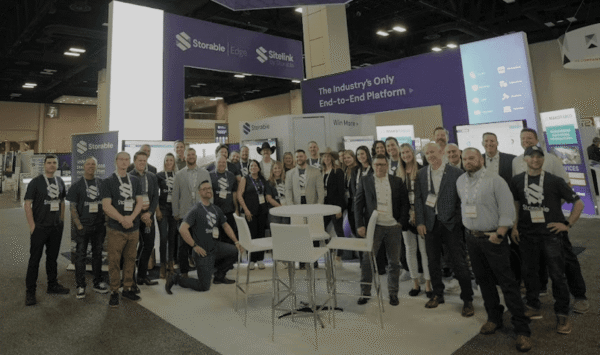 A group of people poses in front of a trade show booth with signage for Storable, SiteLink, and Edge at a convention center.