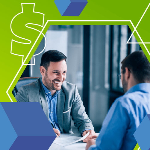 Two men in business attire sitting across a desk, engaged in a conversation. The image has a green and blue geometric overlay with a dollar sign graphic.