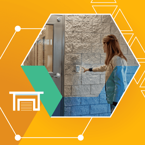 Person pressing a button on a wall-mounted device outside a modern building entrance, set against a graphic background with geometric shapes.