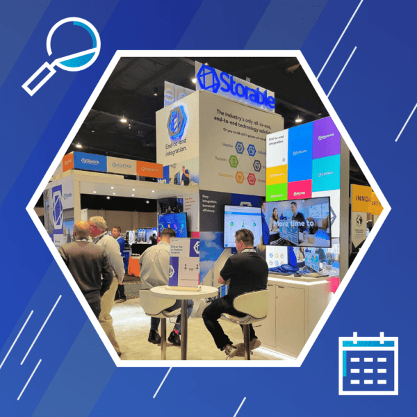 People at a trade show booth featuring colorful digital displays and signage for "Storable," with two seated individuals facing screens.