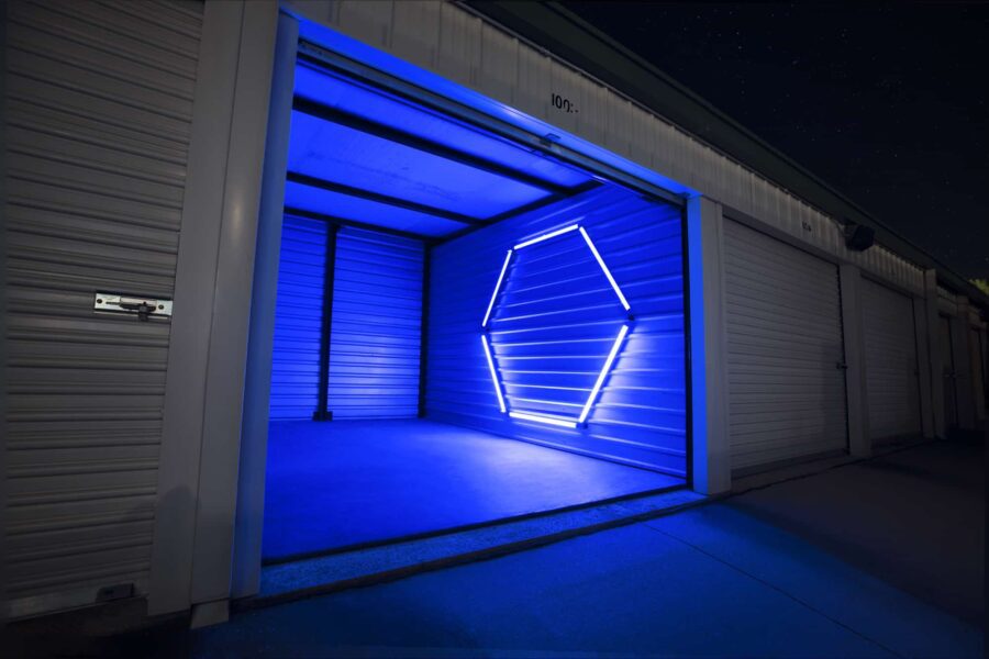 Open storage unit with blue neon hexagonal light on the back wall, surrounded by closed units in a row.