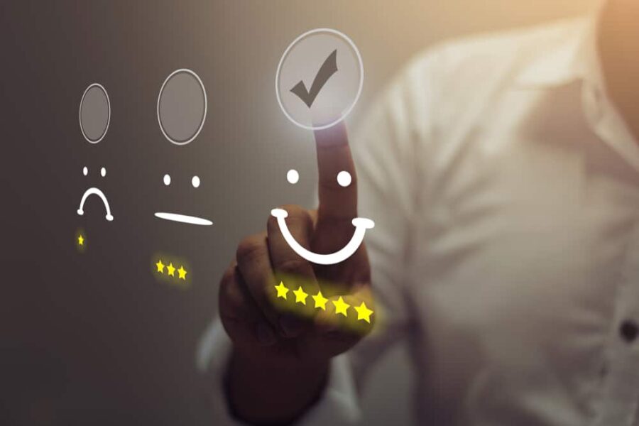 A person in a white shirt presses a smiley face with a checkmark and five stars on a rating scale.