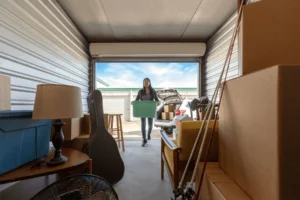 Tenant walking into a filled up storage unit with a box in her hands