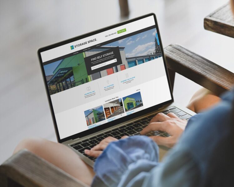 Person using a laptop displaying a self-storage company's website with search and location options on the homepage.