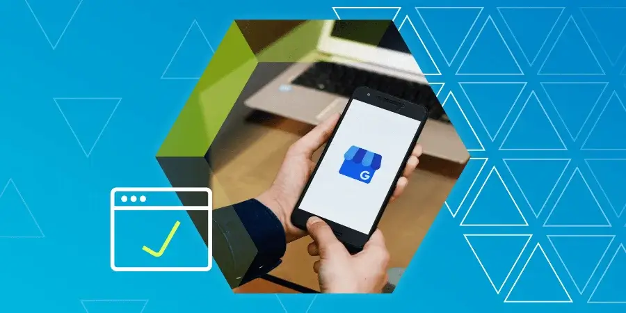 Person holding a smartphone displaying the Google My Business app, with a laptop in the background and blue geometric patterns overlayed.